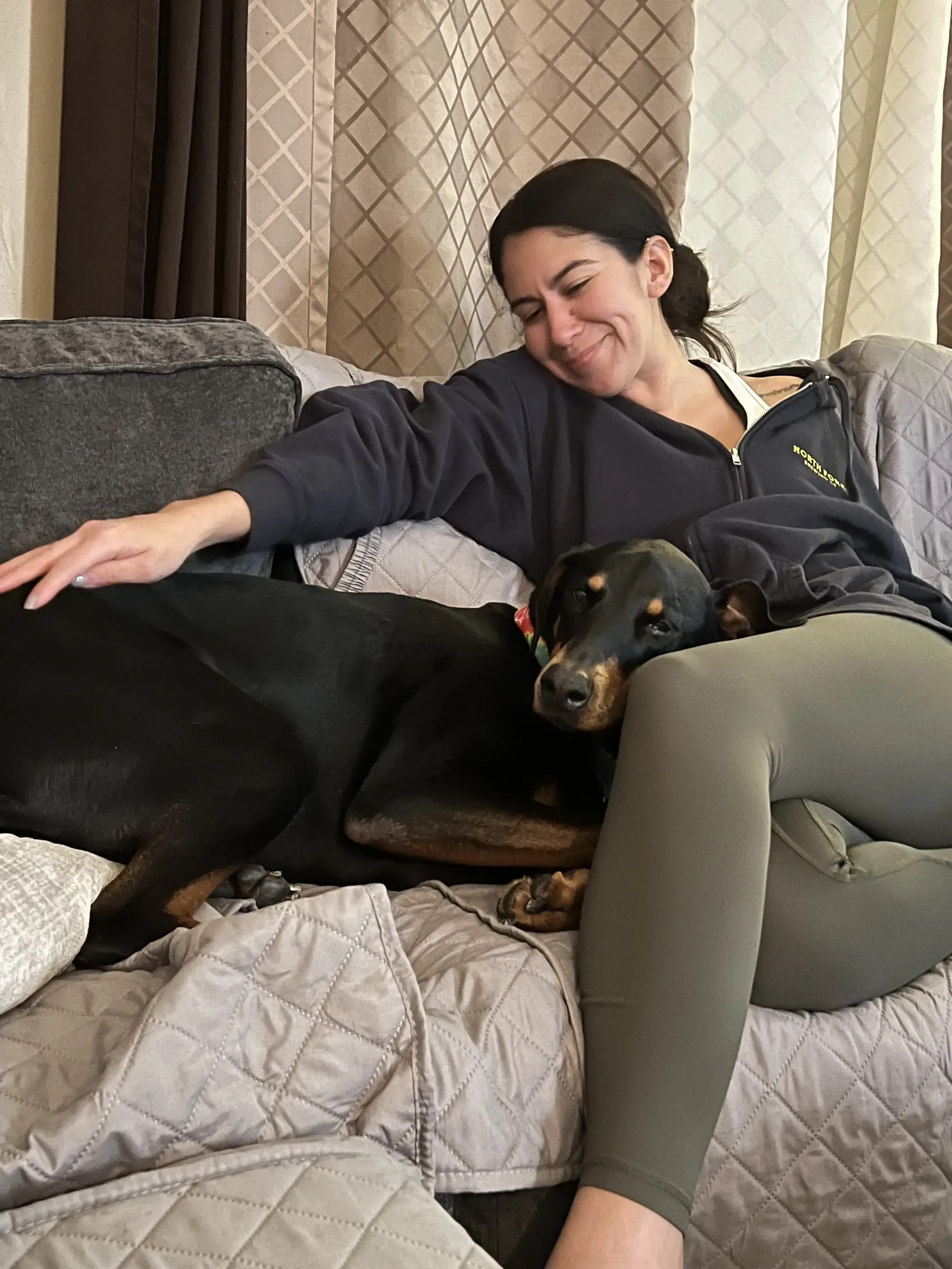 A woman sitting on a couch with her dog